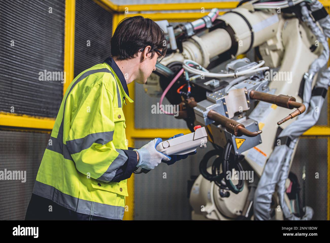 lead engineer working in advanced technology automation factory service checking program robot welding arm Stock Photo