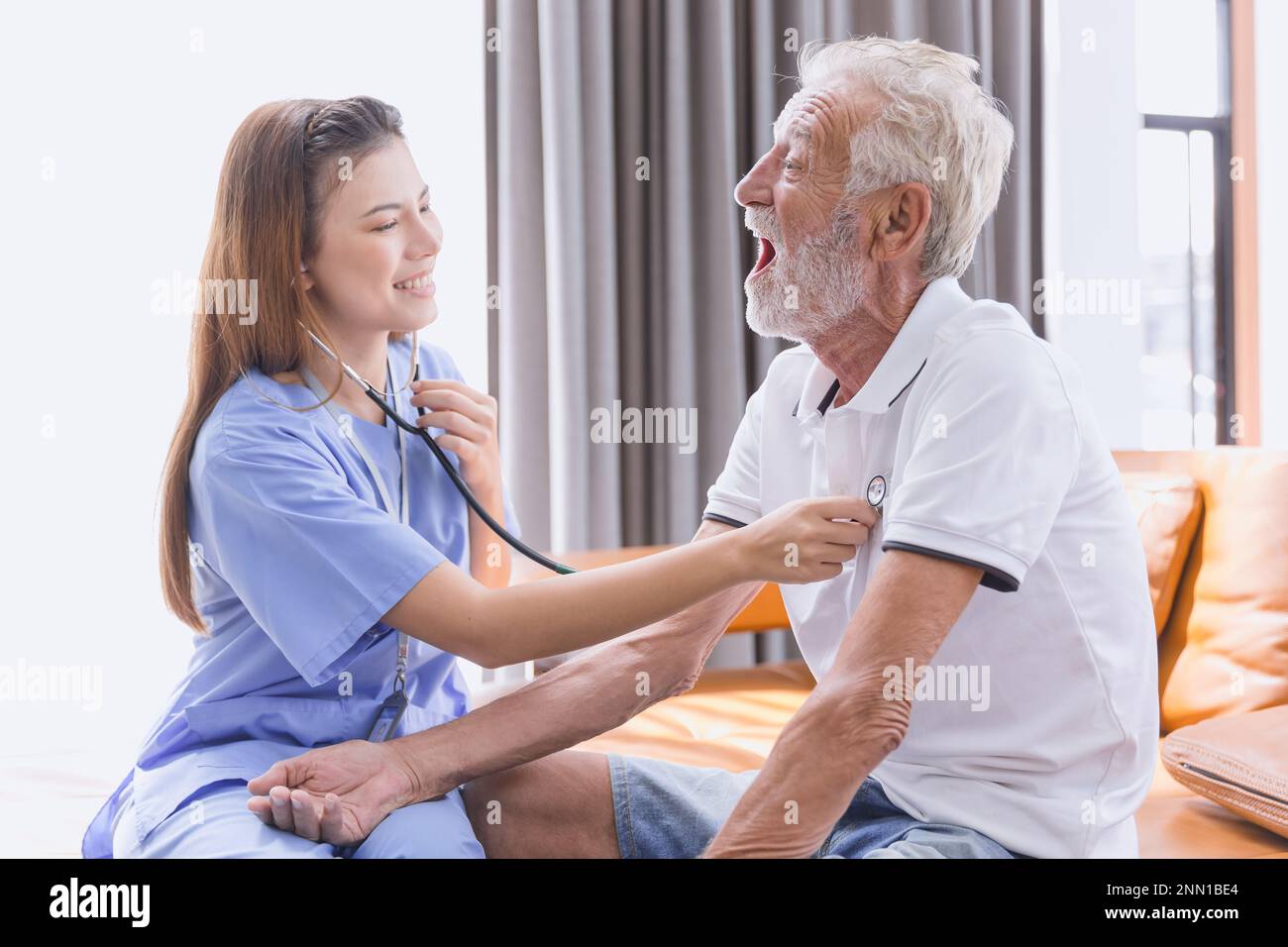 Nurse doctor working at home care medical checkup healthy elderly senior male happy smile Stock Photo