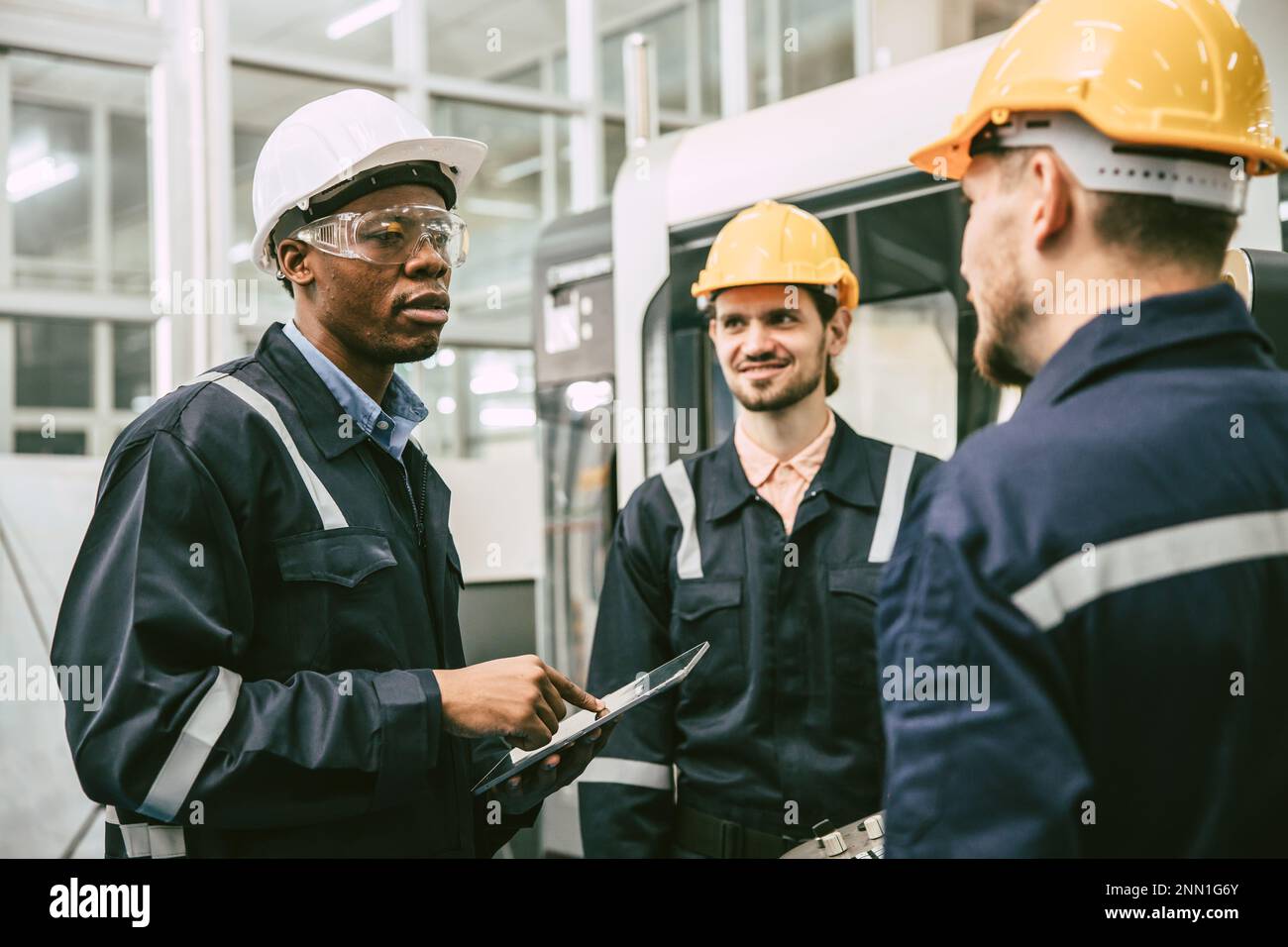 African black male engineer team leader talking with team worker college group in modern factory Stock Photo
