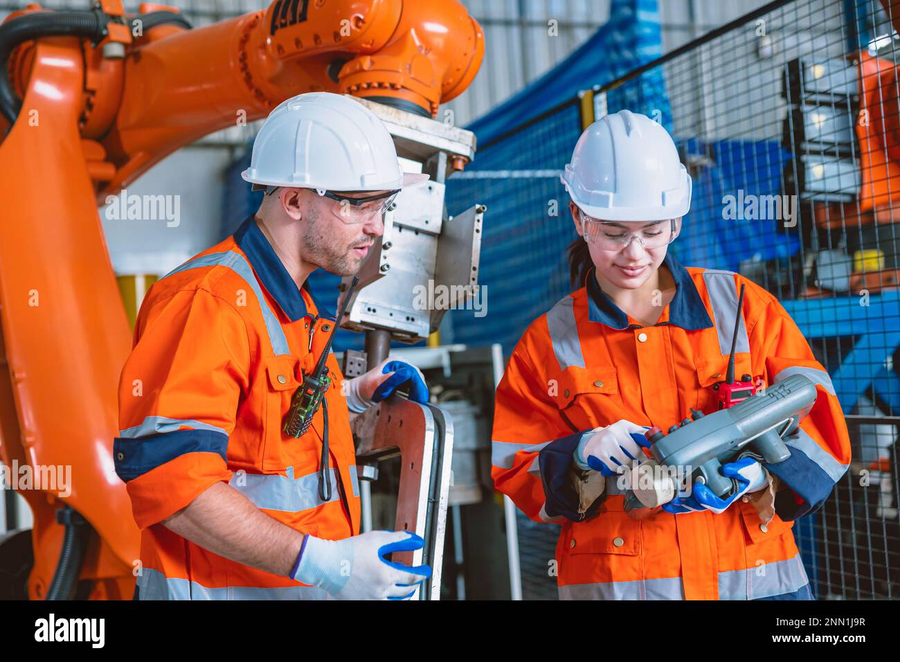 engineer team worker working program robot arm assembly machine in modern metal heavy industry factory Stock Photo