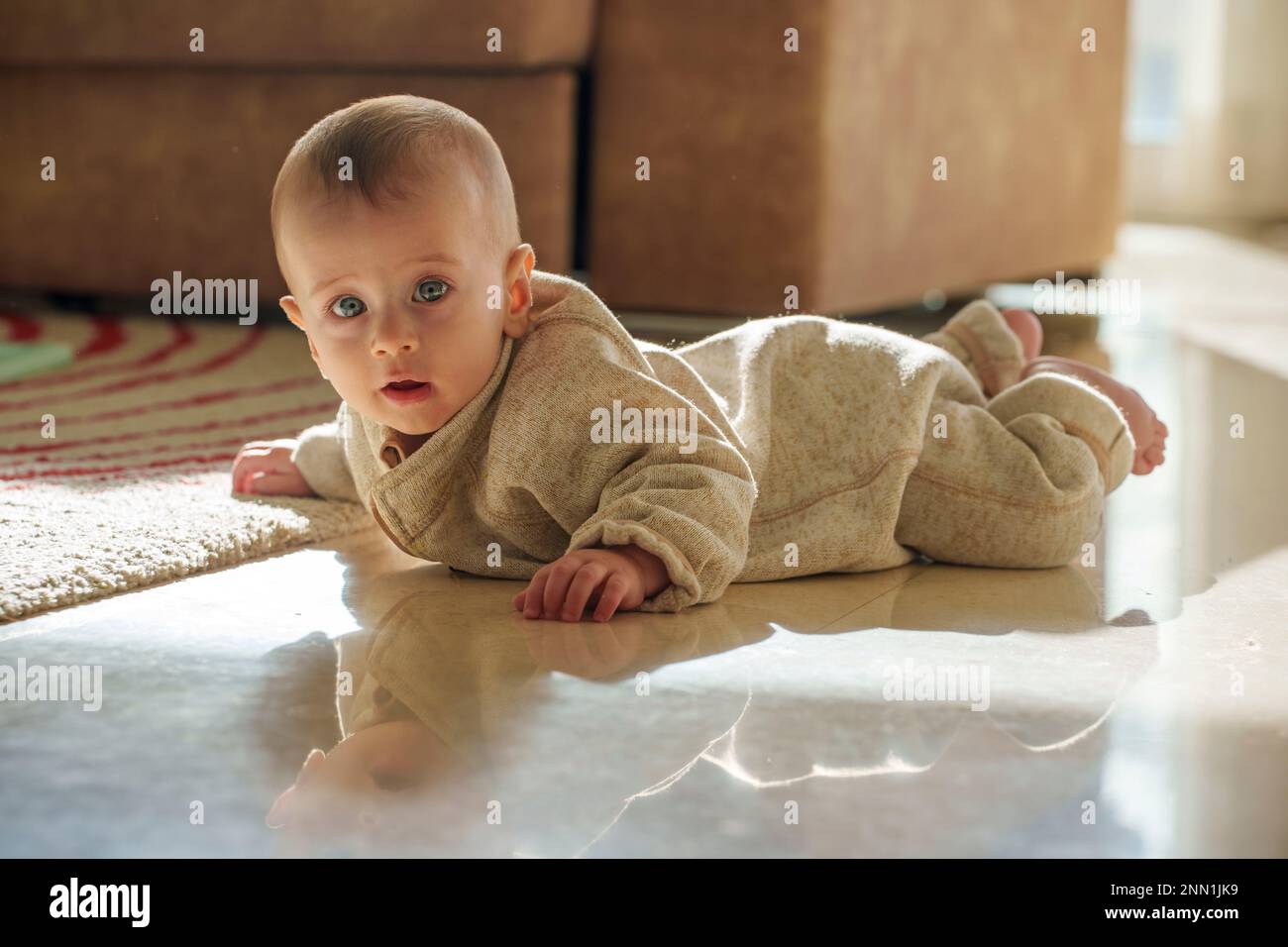 Baby crawling on tiled floor Stock Photo