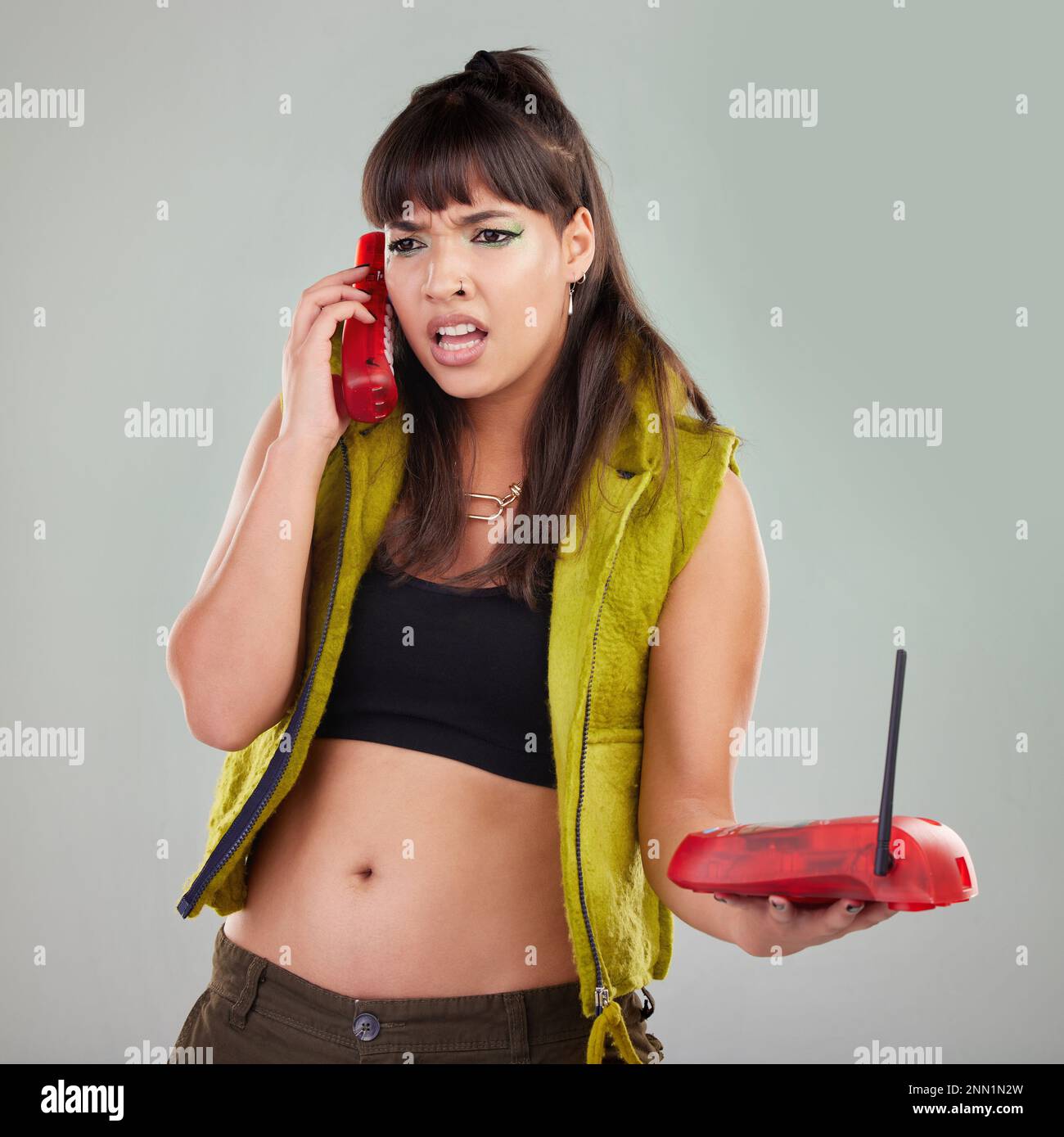 Angry, problem and woman with a telephone for a conversation isolated on a grey studio background. Stress, frustrated and mad girl speaking on a Stock Photo