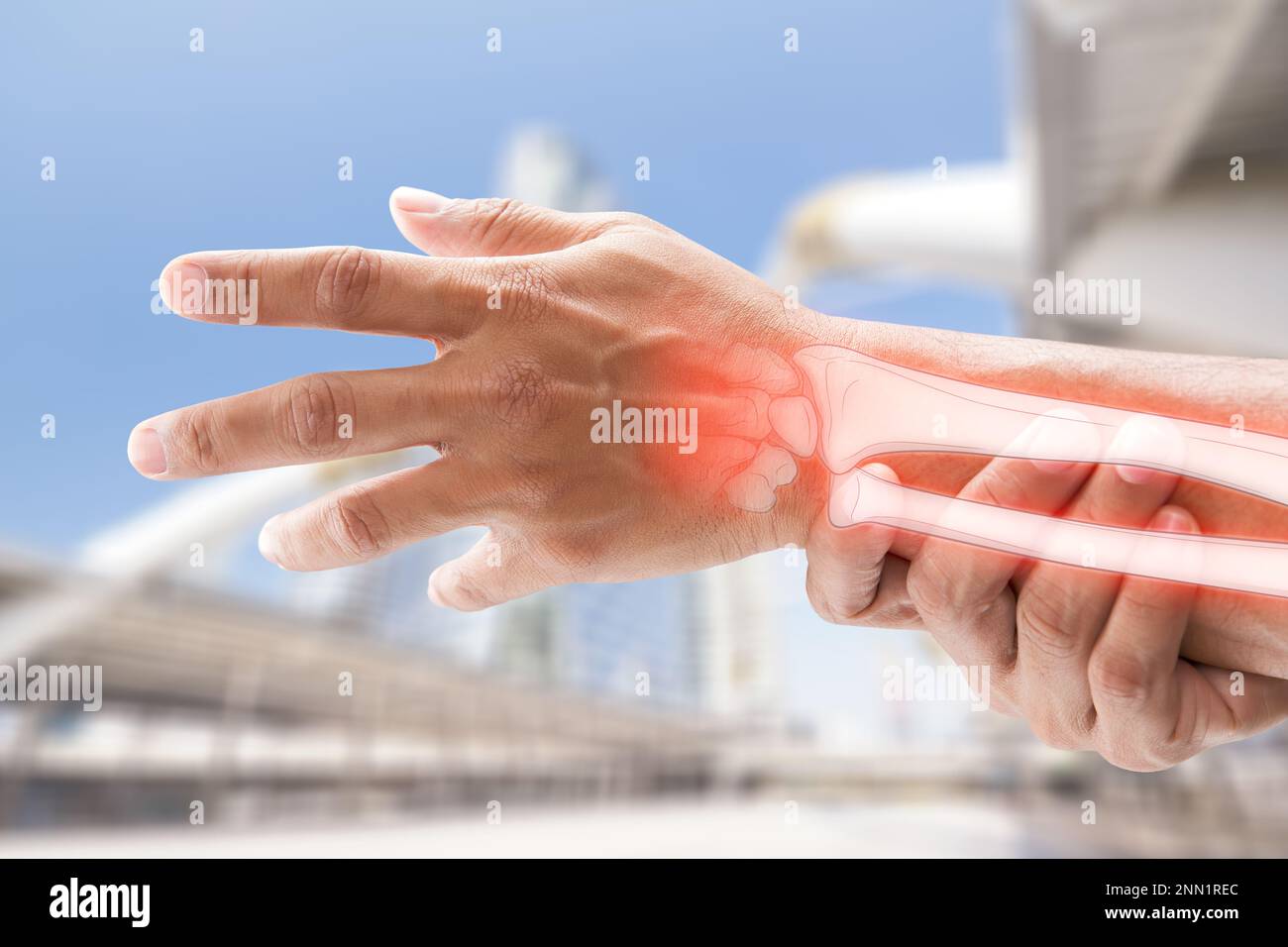 A man massaging painful wrist on a gray background. Pain concept. Osteoporosis Stock Photo