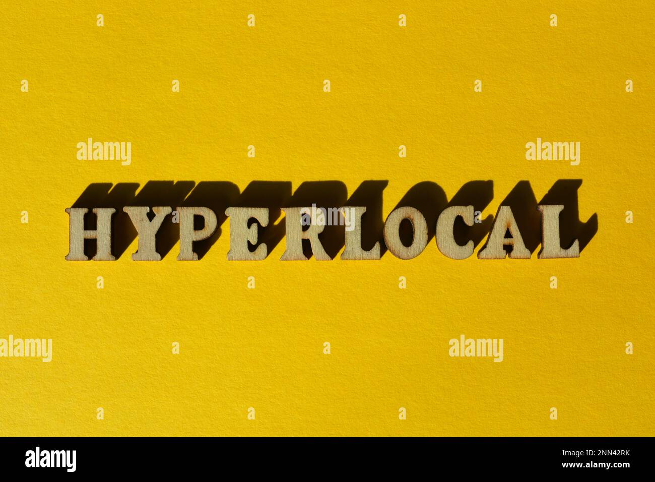 Hyperlocal, word in wooden alphabet letter isolated on yellow background Stock Photo