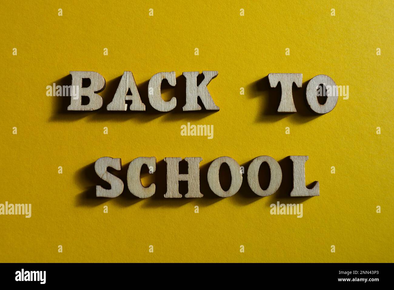 Back To School, words in wooden alphabet letters isolated on yellow background Stock Photo