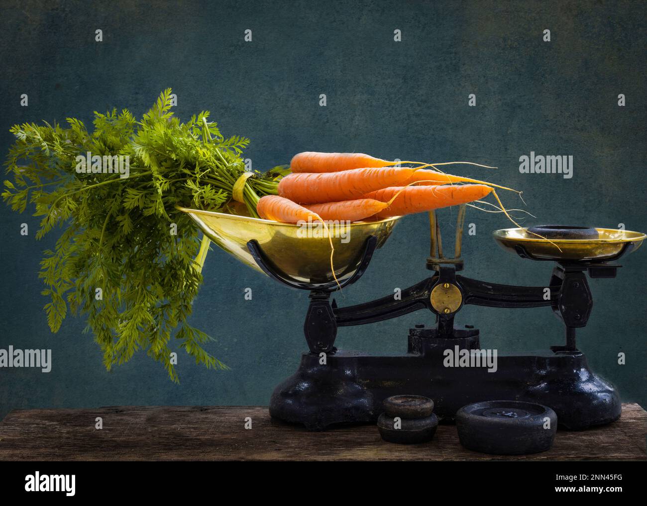 A bunch of carrots with leaves being weighed on an old fashioned, traditional set of imperial weight scales Stock Photo