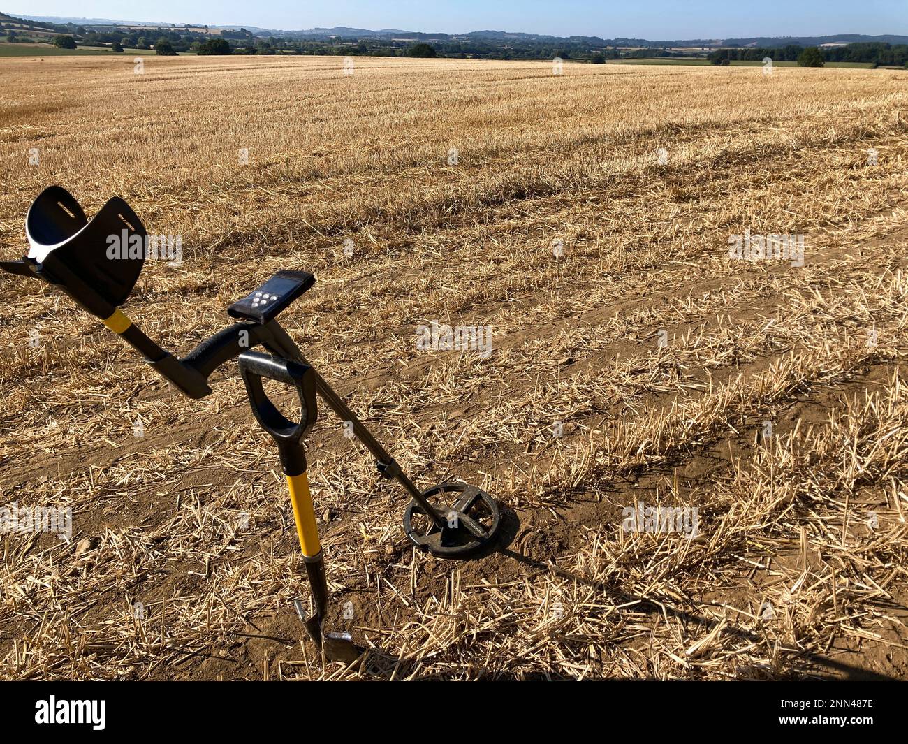 Metal detector and spade in landscape of harvested stubble field, Somerset, UK Stock Photo