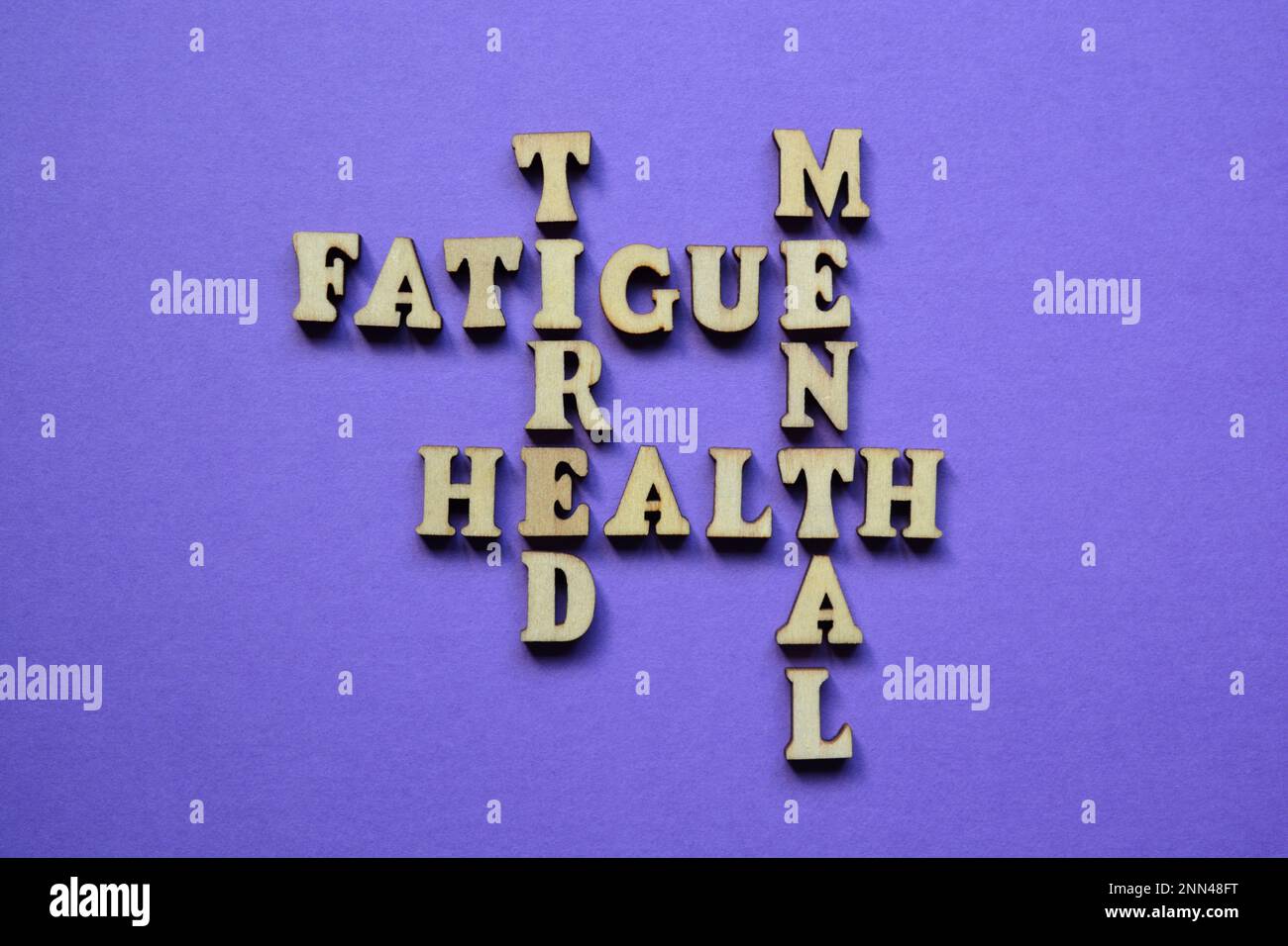 Mental, Health, Tired, Fatigue, words in wooden alphabet letters in crossword form isolated on purple background Stock Photo