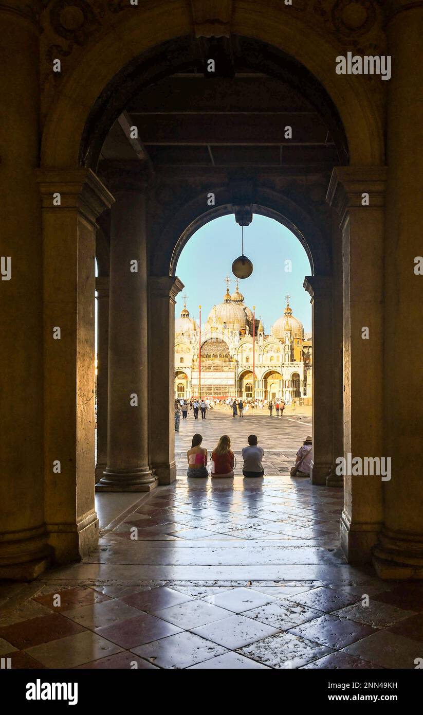 The arcade of the Ala Napoleonica in St Mark's Square with the Basilica of St Mark in the background, Venice, Veneto, Italy Stock Photo
