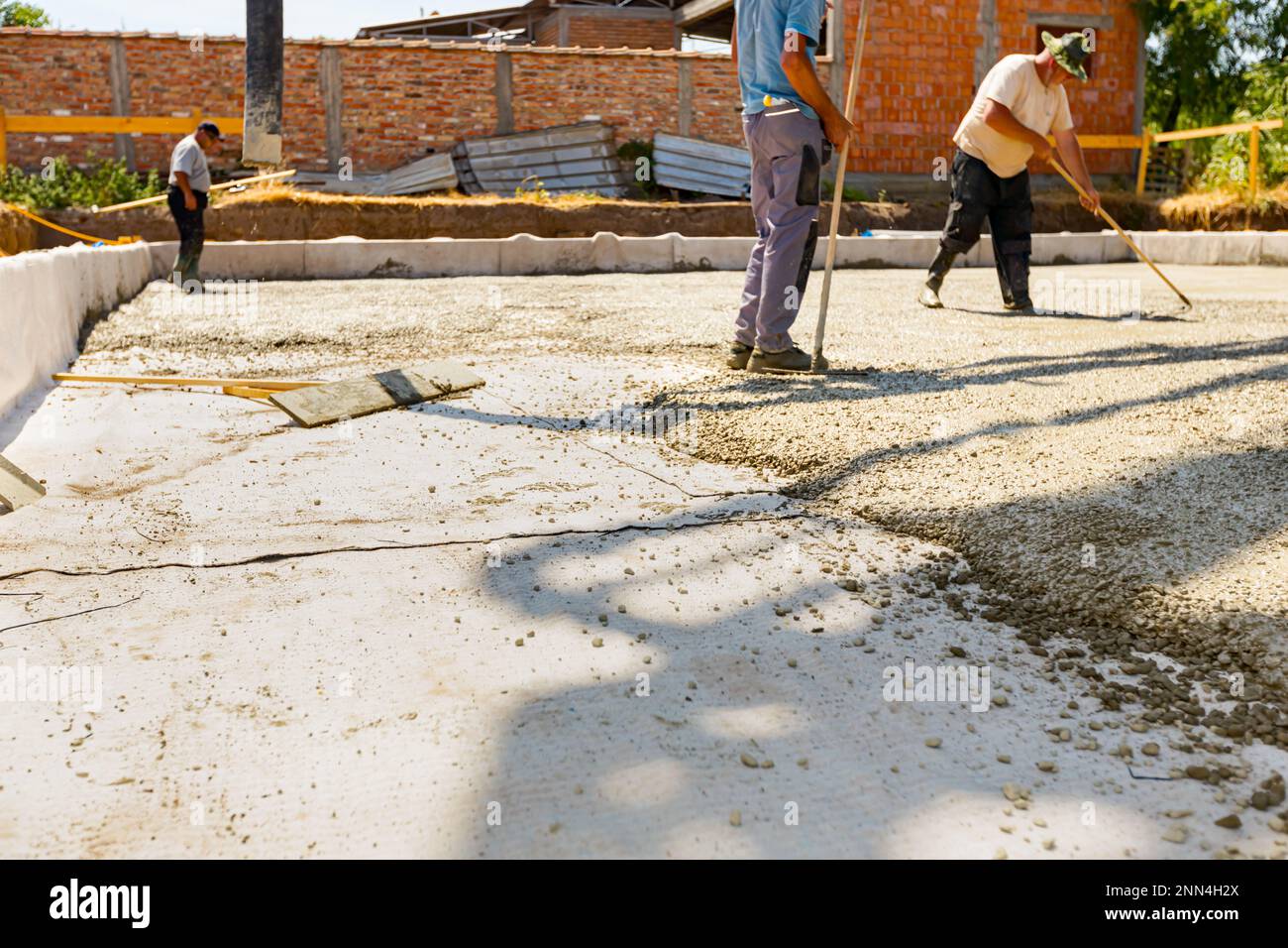 Construction workers, masons are using rake to spreading, leveling