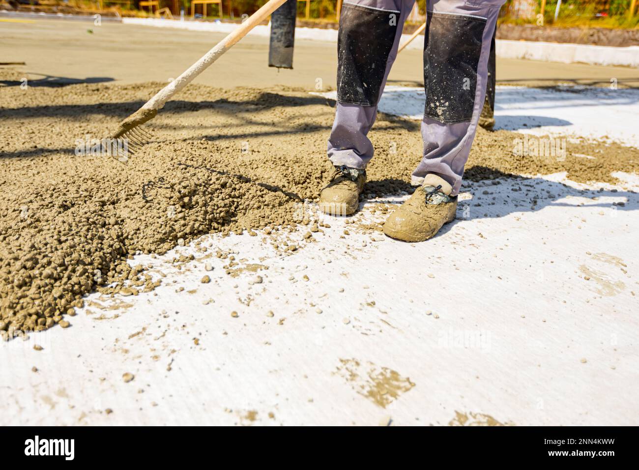 Construction worker, rigger is using rake to spreading, leveling