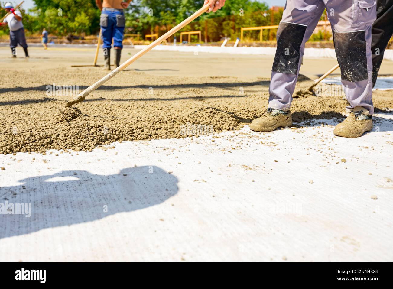 Construction worker, rigger is using rake to spreading, leveling
