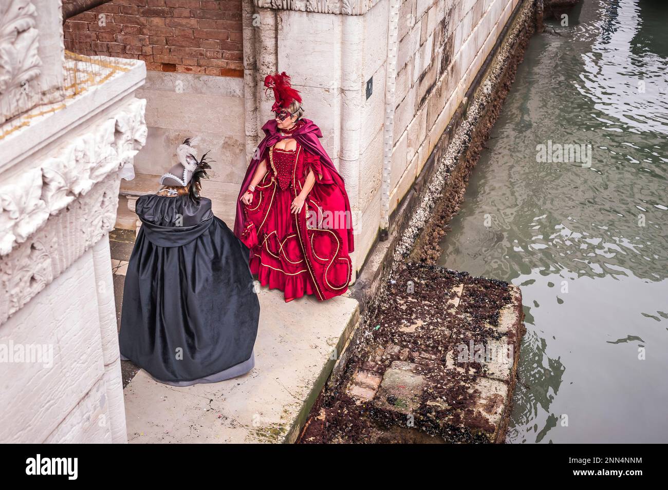 Couple of carnival masked women in Venice under an historical arch Stock Photo