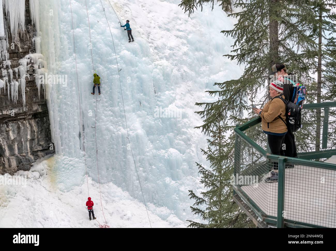 Banff National Park, Alberta, Canada – February 12, 2023:  People on an observation deck watch ice climbers on a frozen waterfall in Johnston Canyon Stock Photo