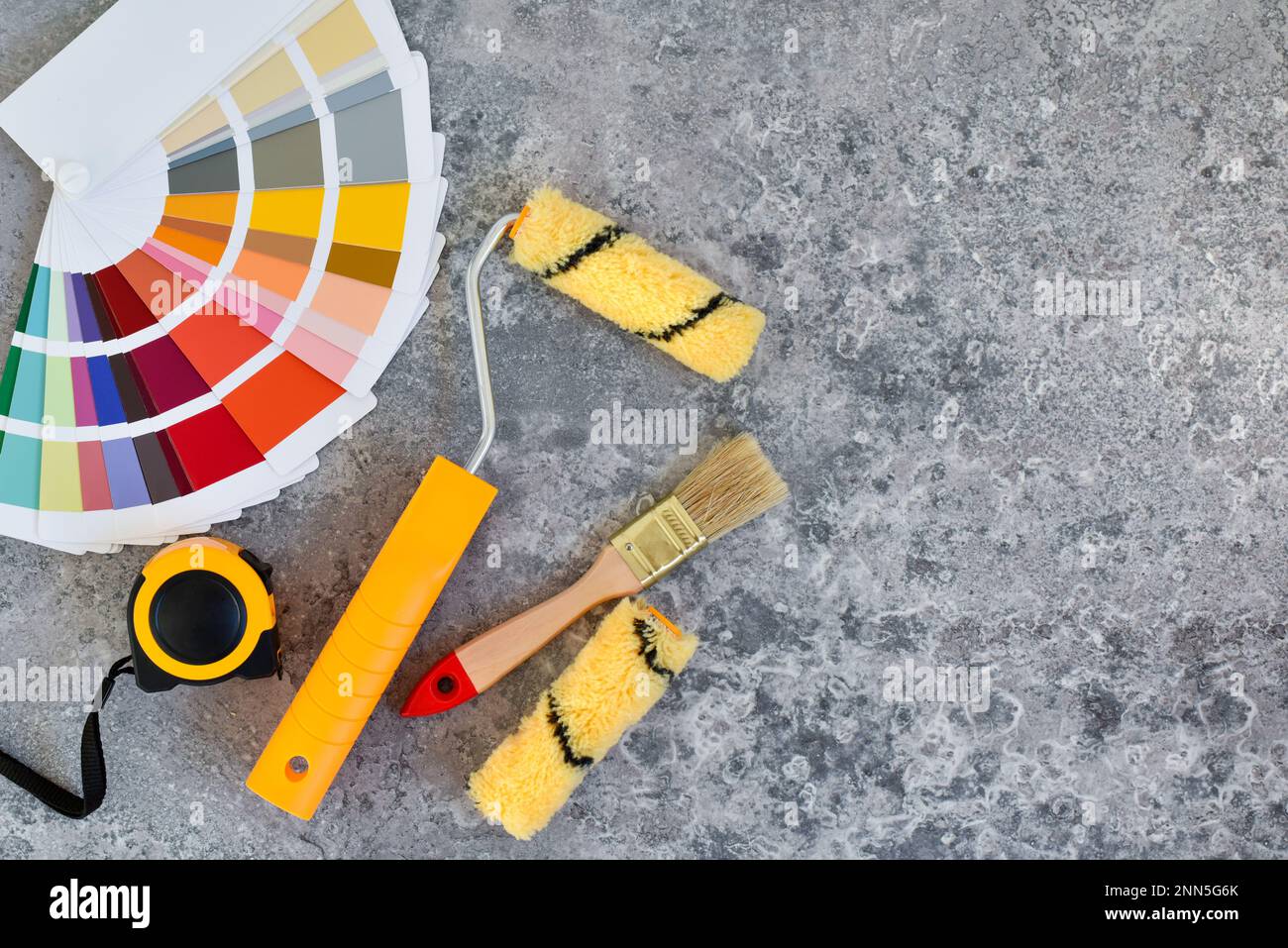 Home paint roller and a paint brushe, color swatches on gray stone background. Top view. Repair housing concept. Stock Photo
