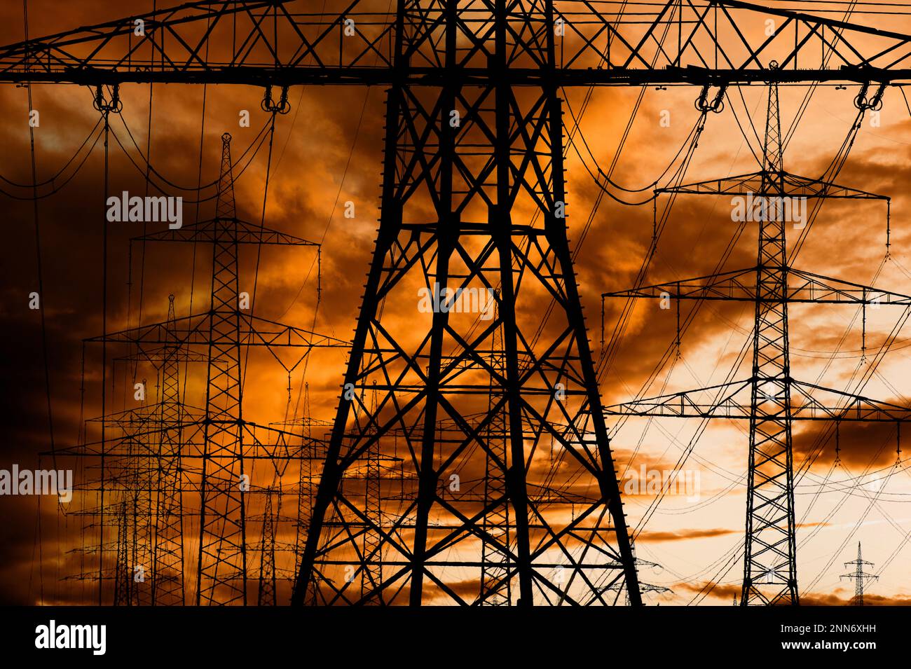 high voltage pylons for electricity and power against sky with dramatic clouds Stock Photo