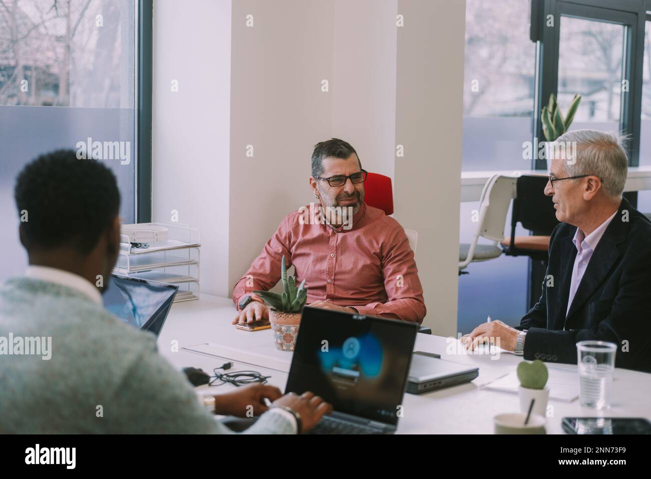 Older business men having a conversation while sitting at the desk at the co working space Stock Photo