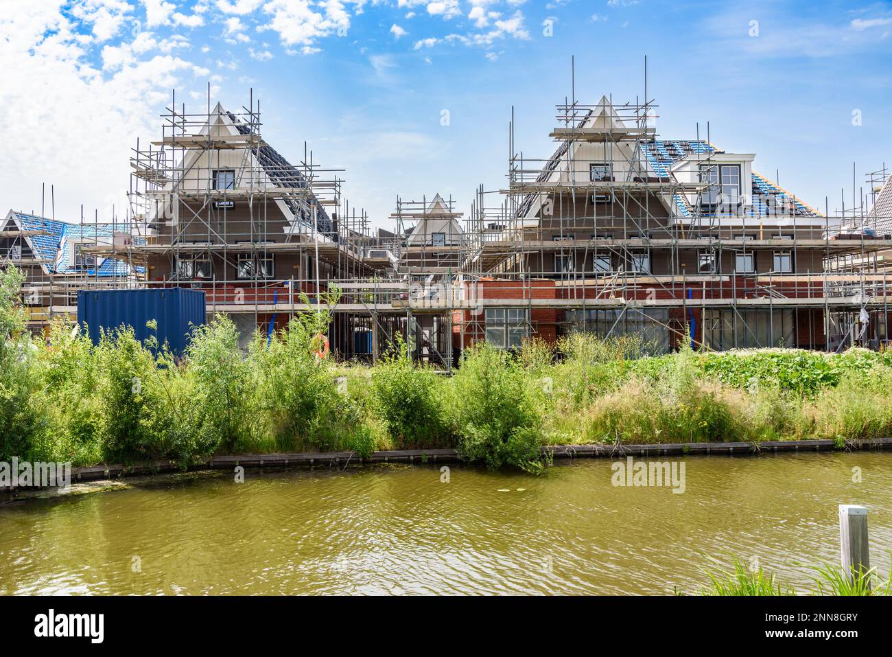 Semi detached houses in construction in a housing development along a canal on a sunny summer day Stock Photo