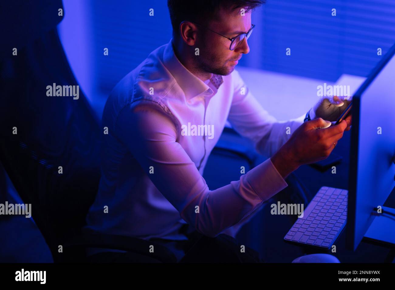 Caucasian Businessman Focused on Data Processing While Working Late in His Office. Business Theme. Stock Photo