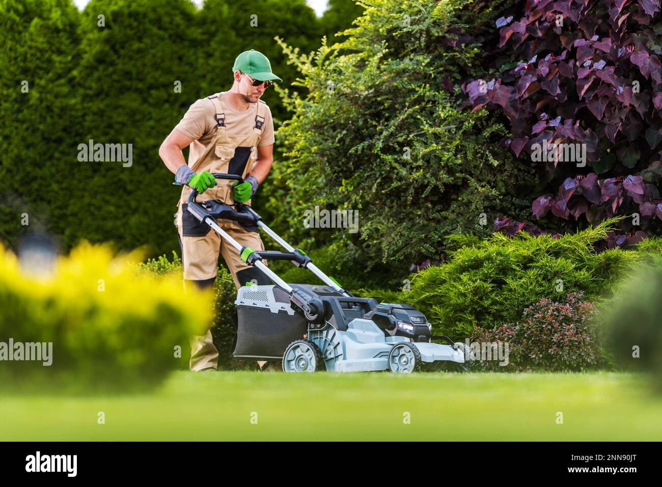 Professional Gardener Mowing the Lawn with Cordless Battery 