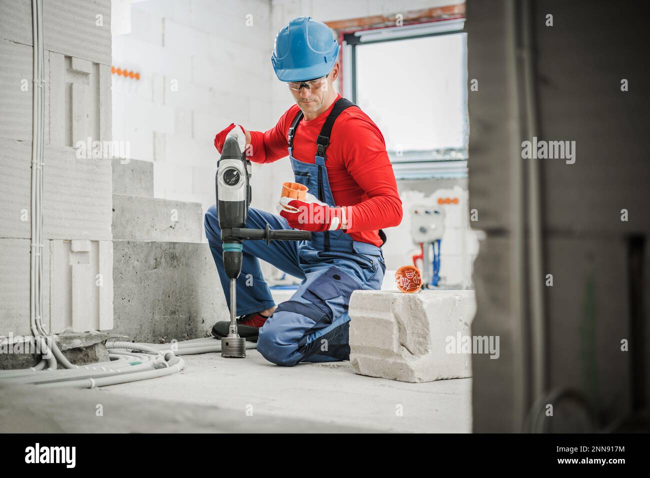 Professional Electrician Holding Power Drill with Hole Saw Attachment and Cable Boxes