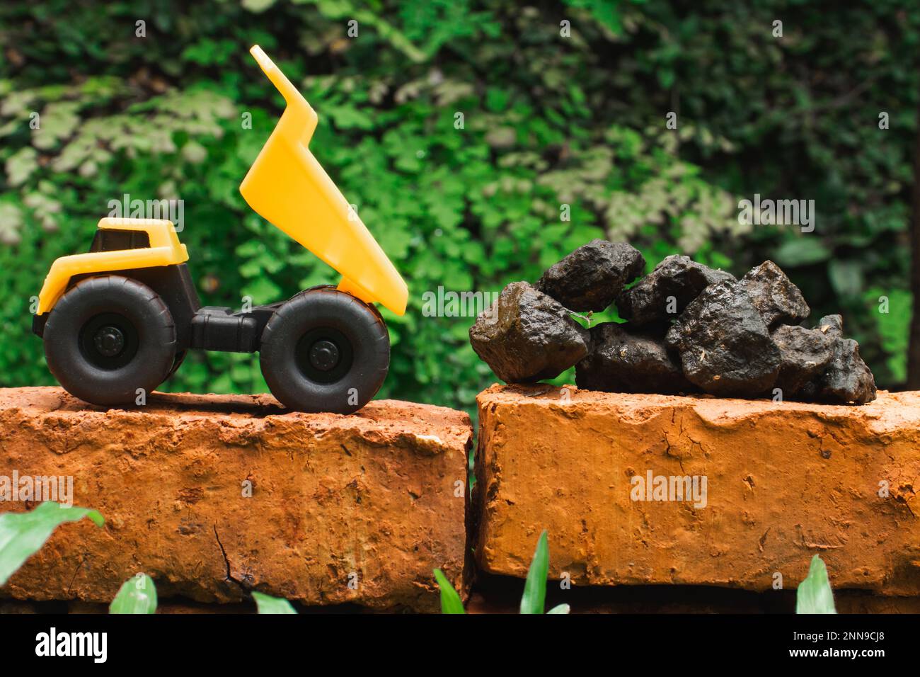 A photo of yellow toy dump truck try to carry pile of stones on a brick, after edited. Stock Photo
