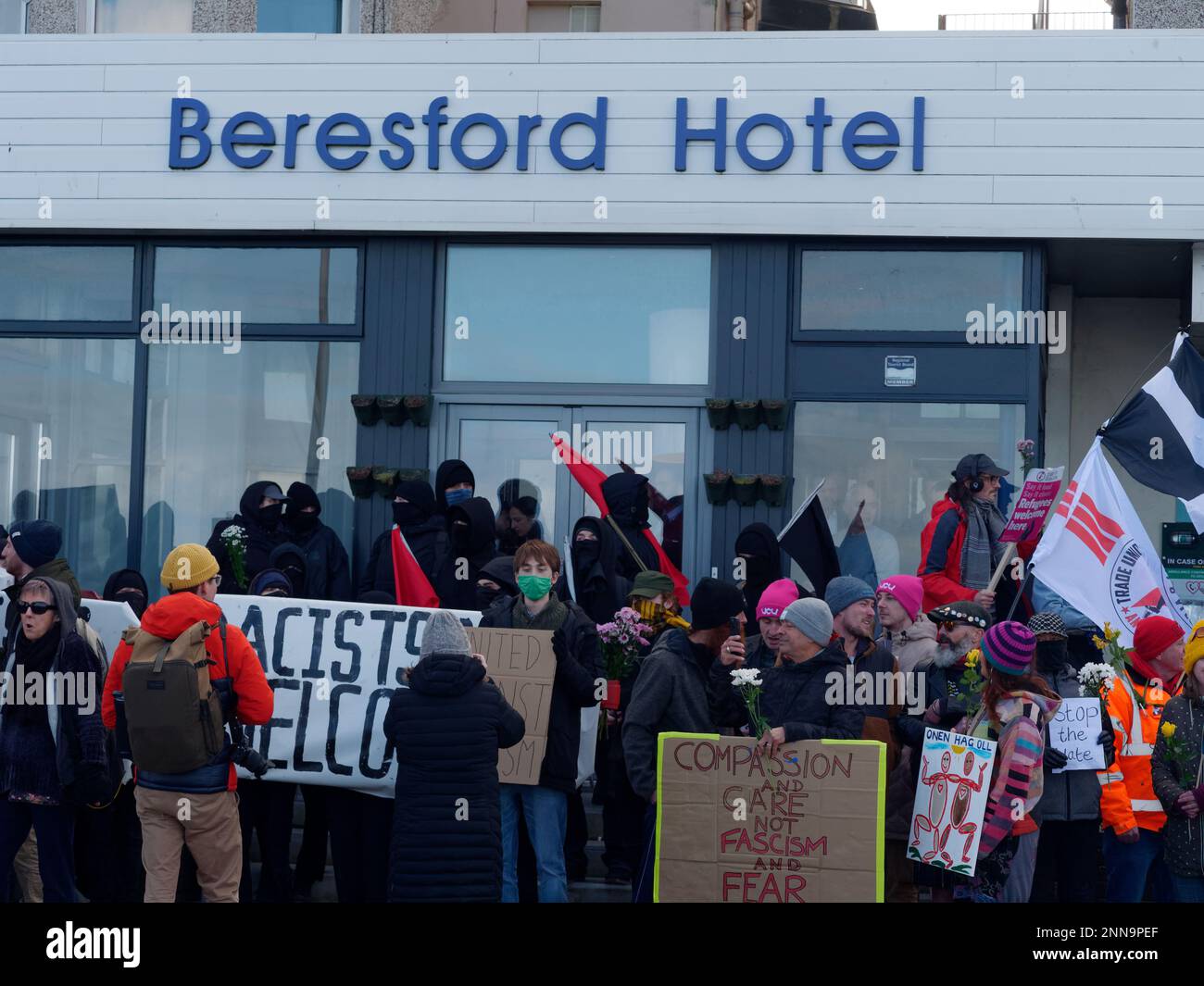 The seafront Hotel Beresford. A Demonstration organised by a right wing group Reform UK against asylum seekers takes place. An undisclosed number of migrants are housed by the home office in the 100 bedroom seaside hotel in Newquay. The hotel is owned by the Bespoke group of hotels and was offered to the Home office for this purpose. Although officially a temporary measure, while the home office processes asylum applications, many of the residents have been here since November 2022. A far larger group of anti Fascist counter demonstrators are also present with placards and flowers confronting Stock Photo