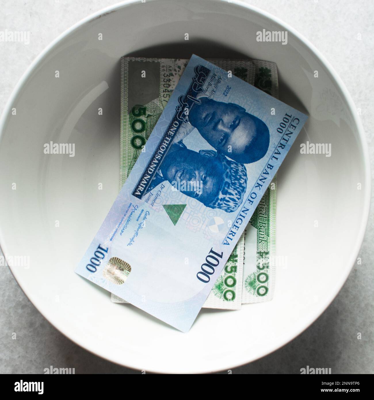 the new Nigerian 1000 and 500 Naira notes in a white bowl, Nigeria's new currency in a bowl Stock Photo