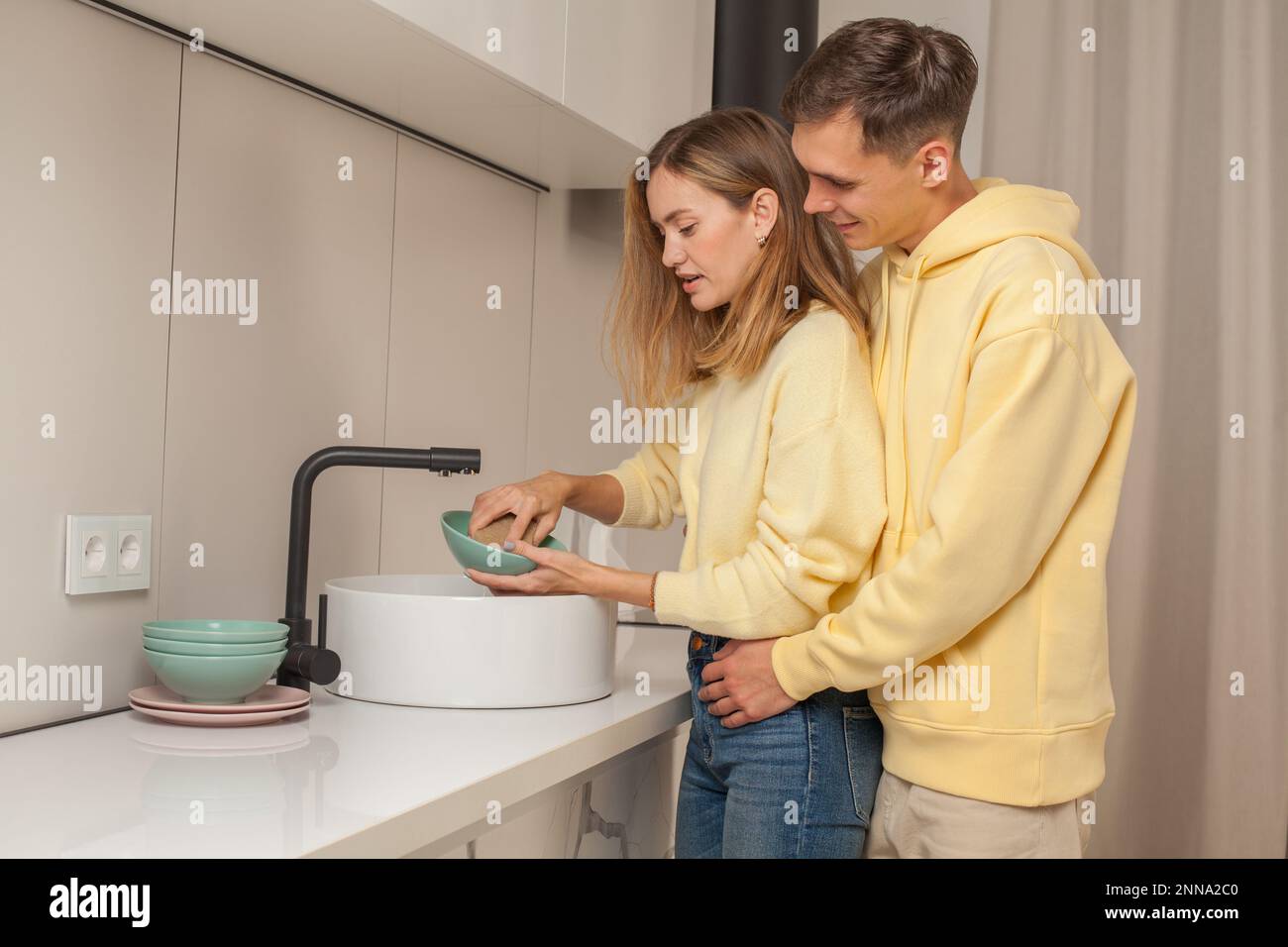 https://c8.alamy.com/comp/2NNA2C0/portrait-of-man-and-woman-couple-hugging-and-washing-the-dishes-together-in-the-kitchen-2NNA2C0.jpg