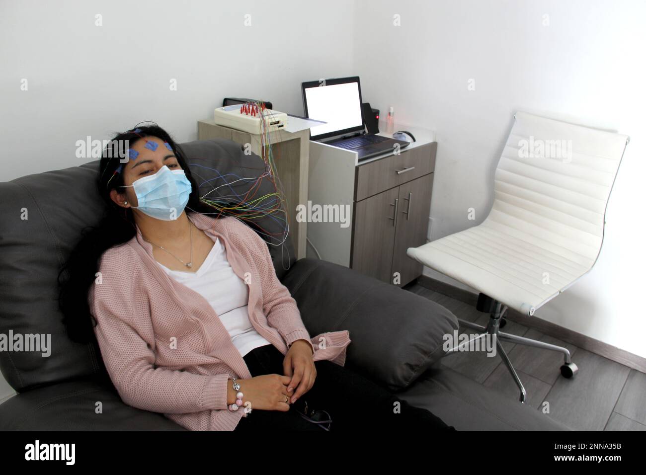 Latin woman with protection mask in medical tests, electroencephalogram and brain mapping in times of covid-19 contingency Stock Photo