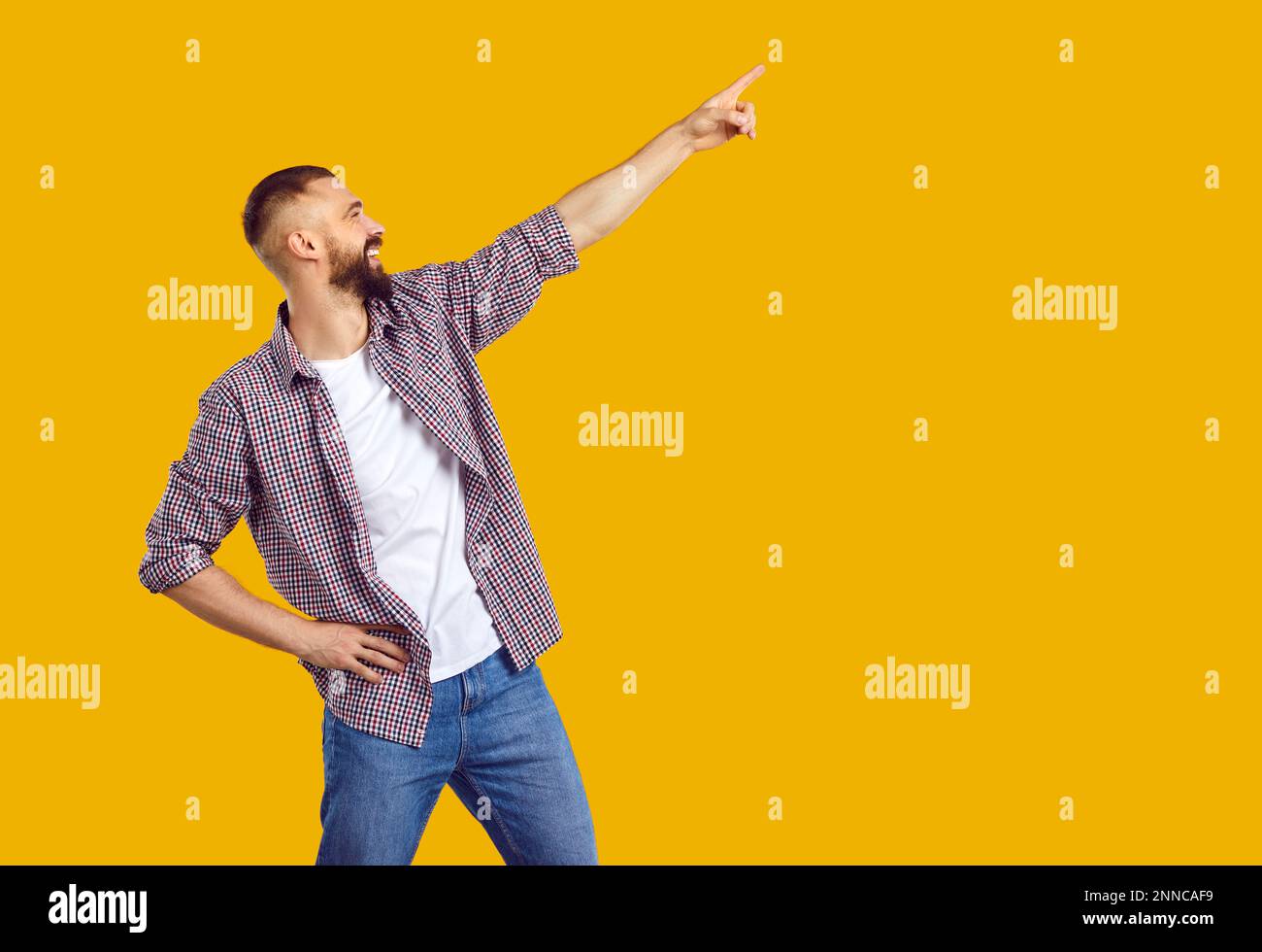 Happy positive young man pointing aside up with finger hand gesture at copy space. Stock Photo