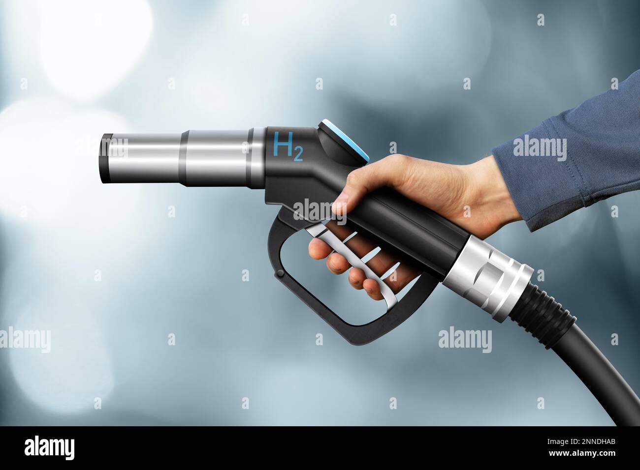 Hand with hydrogen fueling nozzle on a gray background Stock Photo