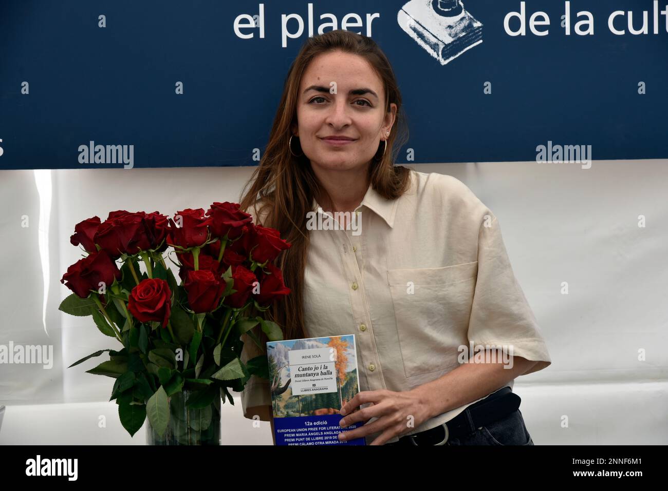 The author Irene Solá with a bouquet of red roses and her book at the book  signing on Sant Jordi's Day, April 23rd, 2021, in Barcelona, Catalonia  (Spain). Although there will be