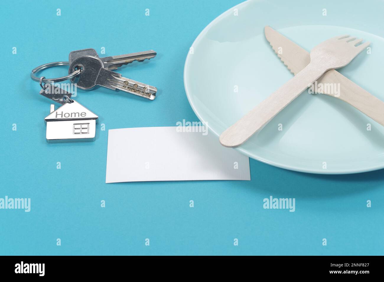 House symbol with silver keys and blank white business card on blue background. Real estate concept Stock Photo