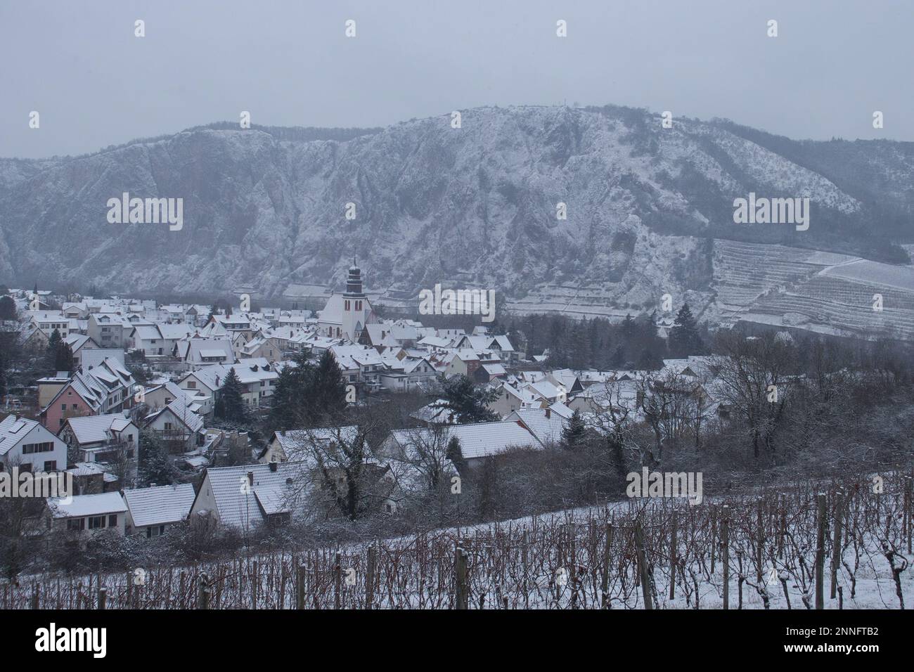 Bad Munster am Stein-Ebernburg, Germany - Febryary 8, 2021: Houses and church in Bad Munster in front of Rotenfels covered in snow on a cold, grey win Stock Photo