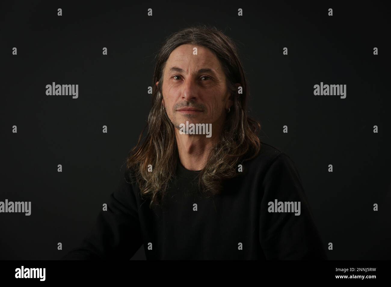 Portrait of middle aged man with long hair on black background Stock Photo