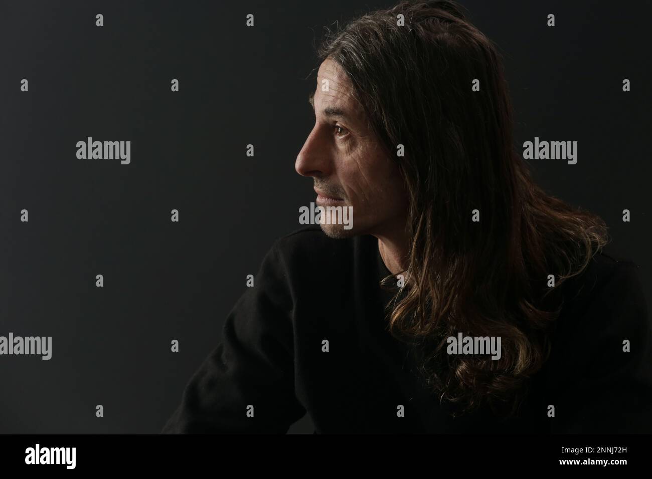 Portrait of middle aged man with long hair on black background Stock Photo