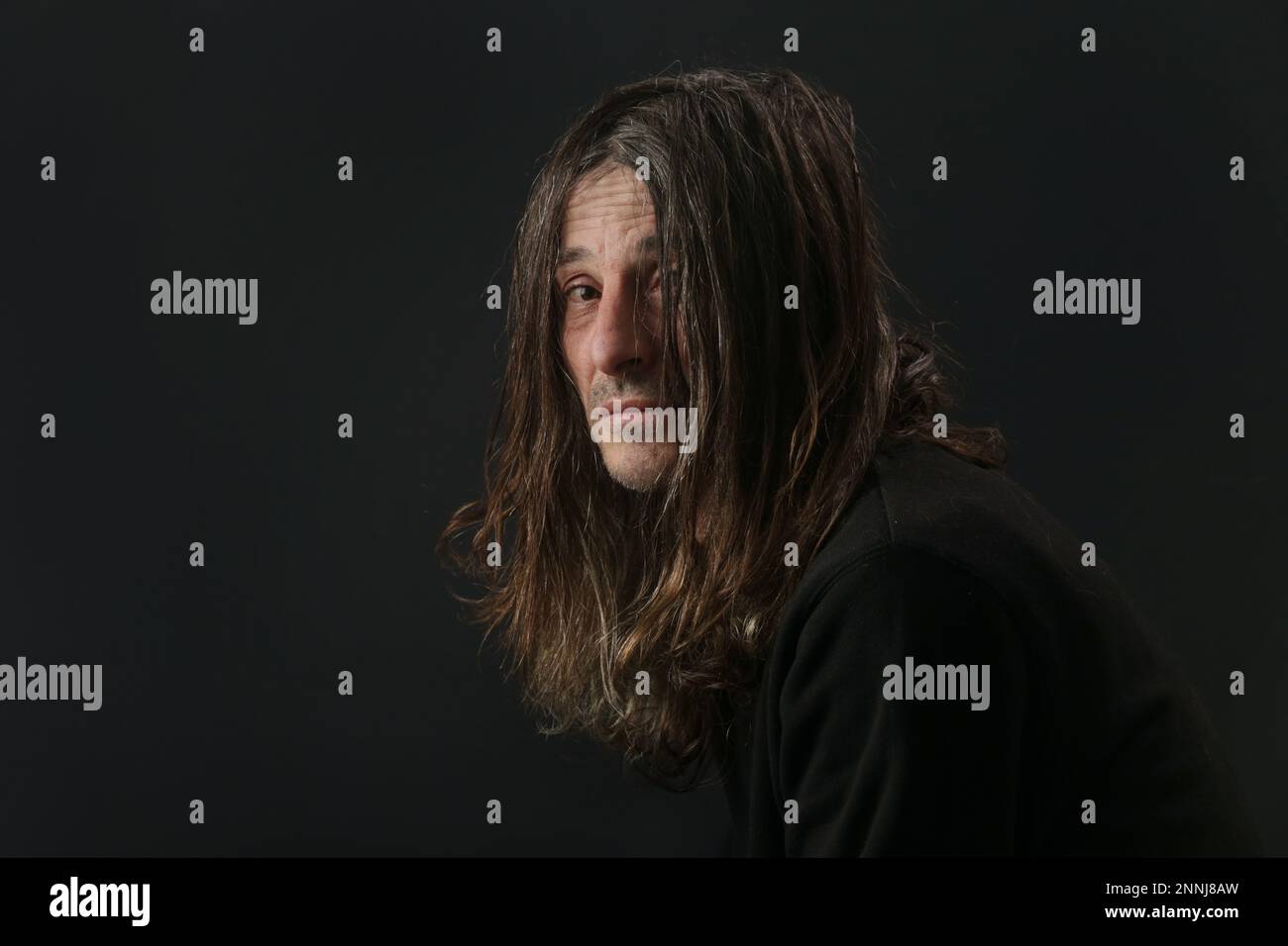 Portrait of middle aged man with long hair on black background Stock Photo