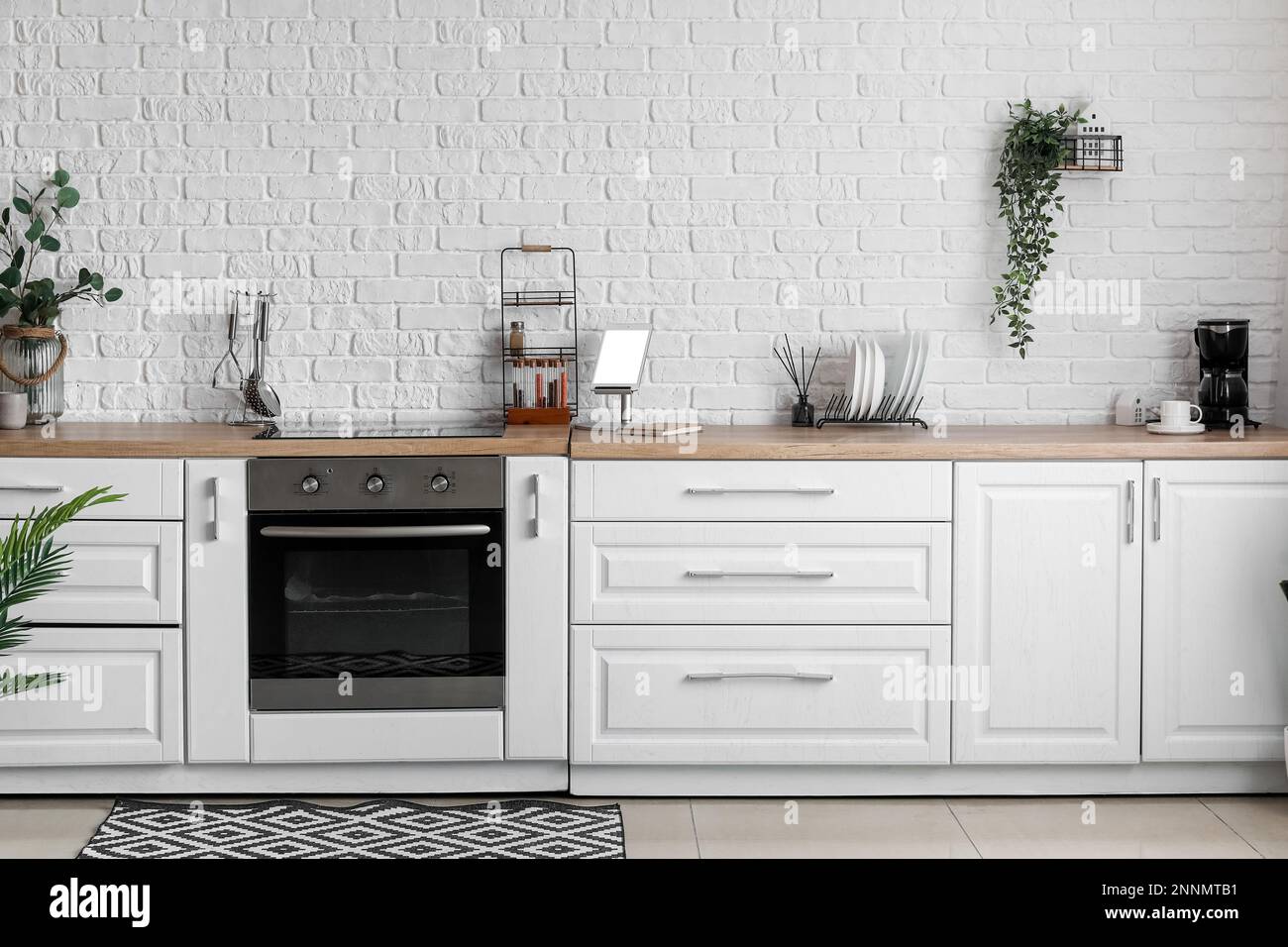 Interior of light kitchen with white counters, electric oven and ...