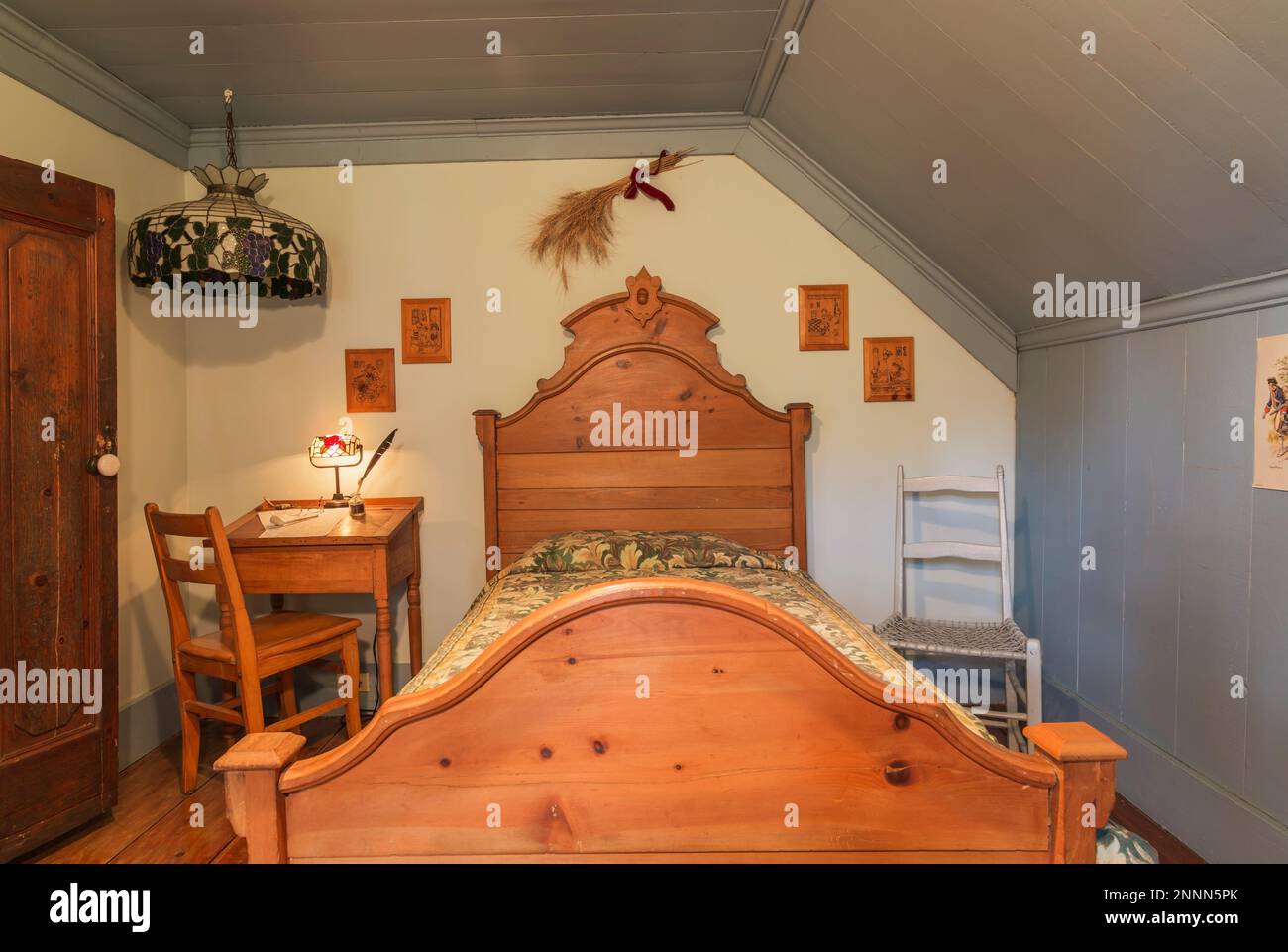 Antique single bed with wooden headboard and footboard, desk with house