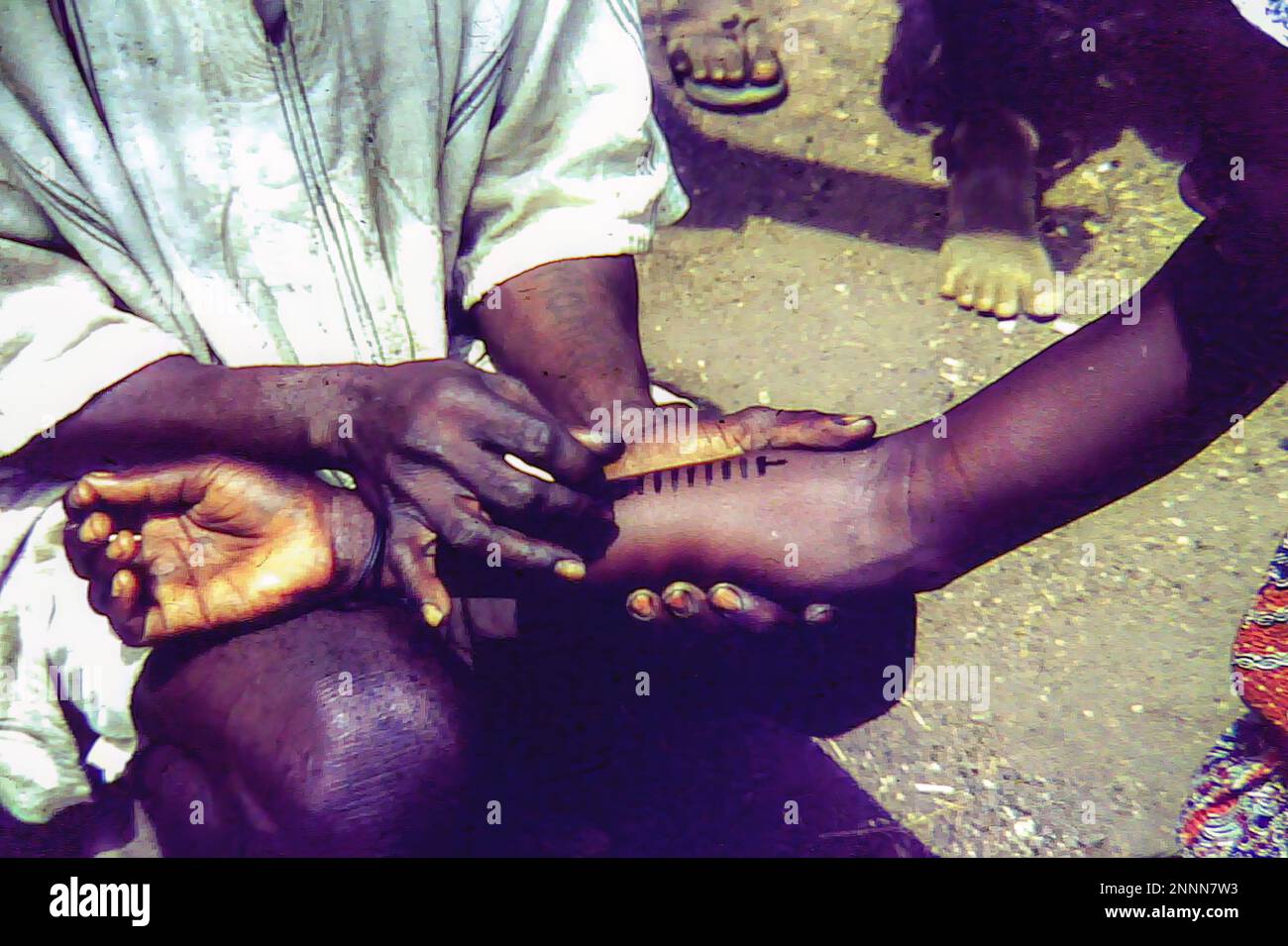 An African women getting at tattoo on her forearm at an outdoor market in Bolgatanga, Ghana c.1958 Stock Photo