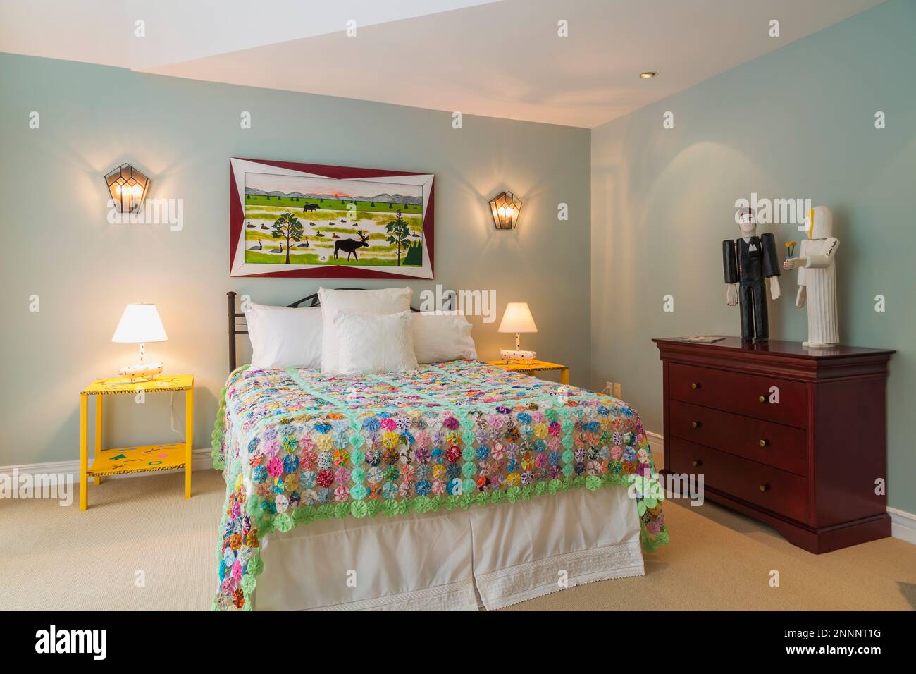 https://c8.alamy.com/comp/2NNNT1G/queen-size-bed-with-black-antique-wrought-iron-headboard-and-colourful-flowery-motif-quilt-bedspread-yellow-folk-art-nightstands-in-bedroom-2NNNT1G.jpg