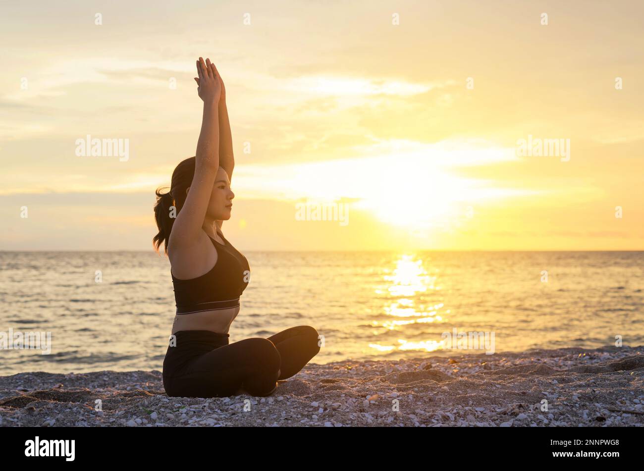Young healthy woman practicing yoga on the beach at sunset. Beach at Chonburi, Thailand. Stock Photo