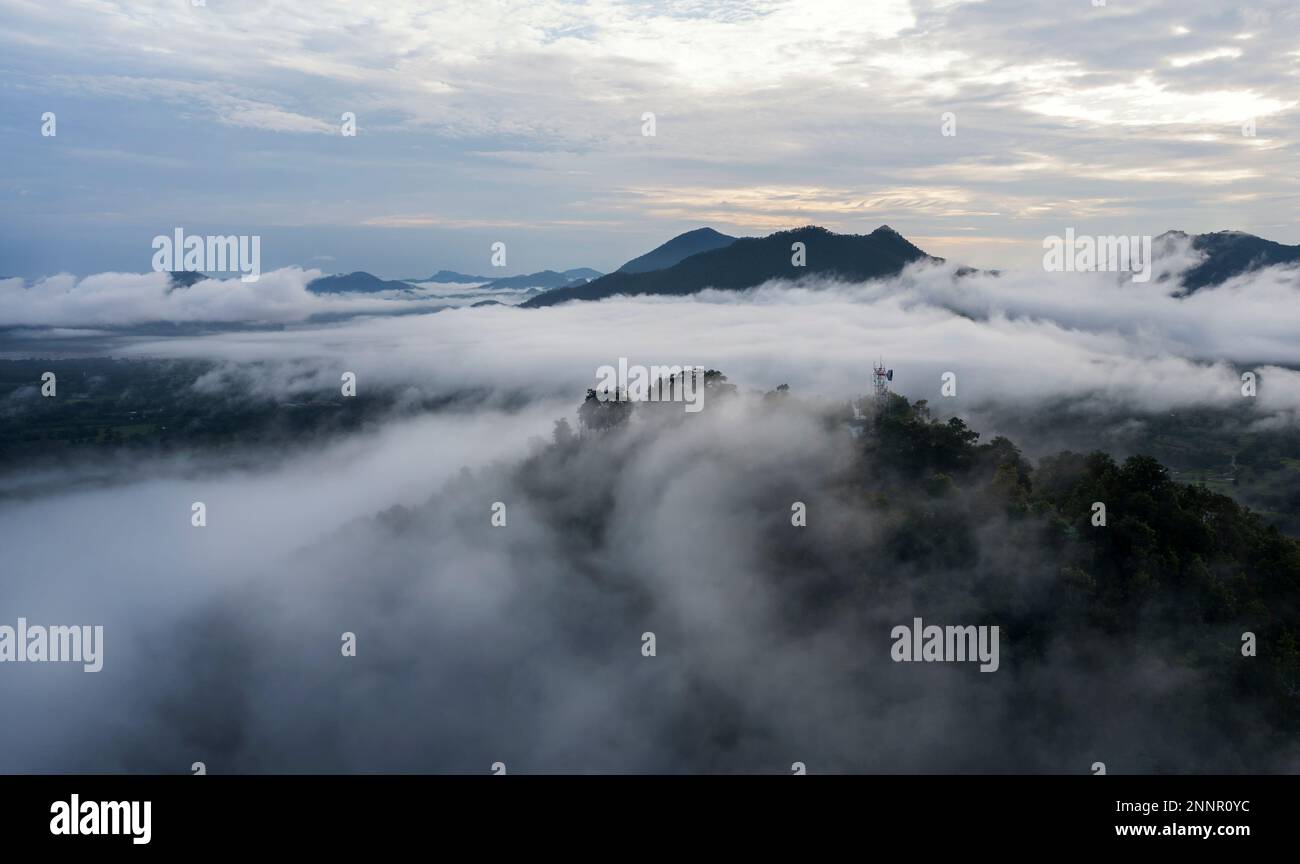 Aerial view drone fly over Sea of fog, Floating sea of clouds like cloud waves on mountains, Sky and clouds. View on the mountain full of fog in the m Stock Photo