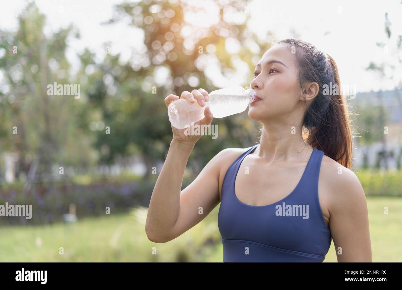 Woman drinking clean water from bottle. Woman workout drink water after running. Female drinking water after exercise or sport. Athlete woman relax an Stock Photo
