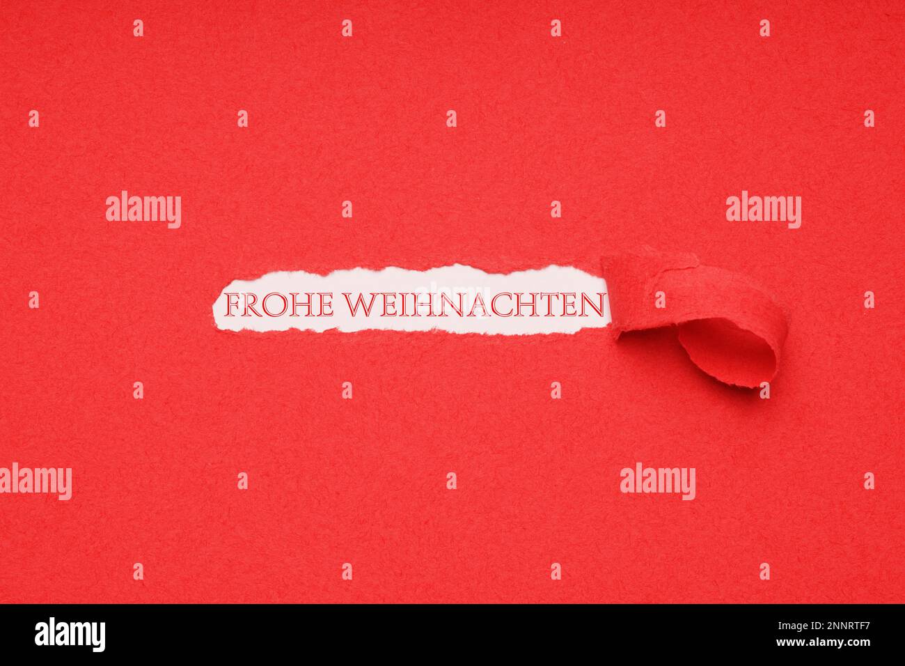 Frohe Weihnachten is German for merry christmas - xmas greeting seen through hole peeled in red paper background Stock Photo