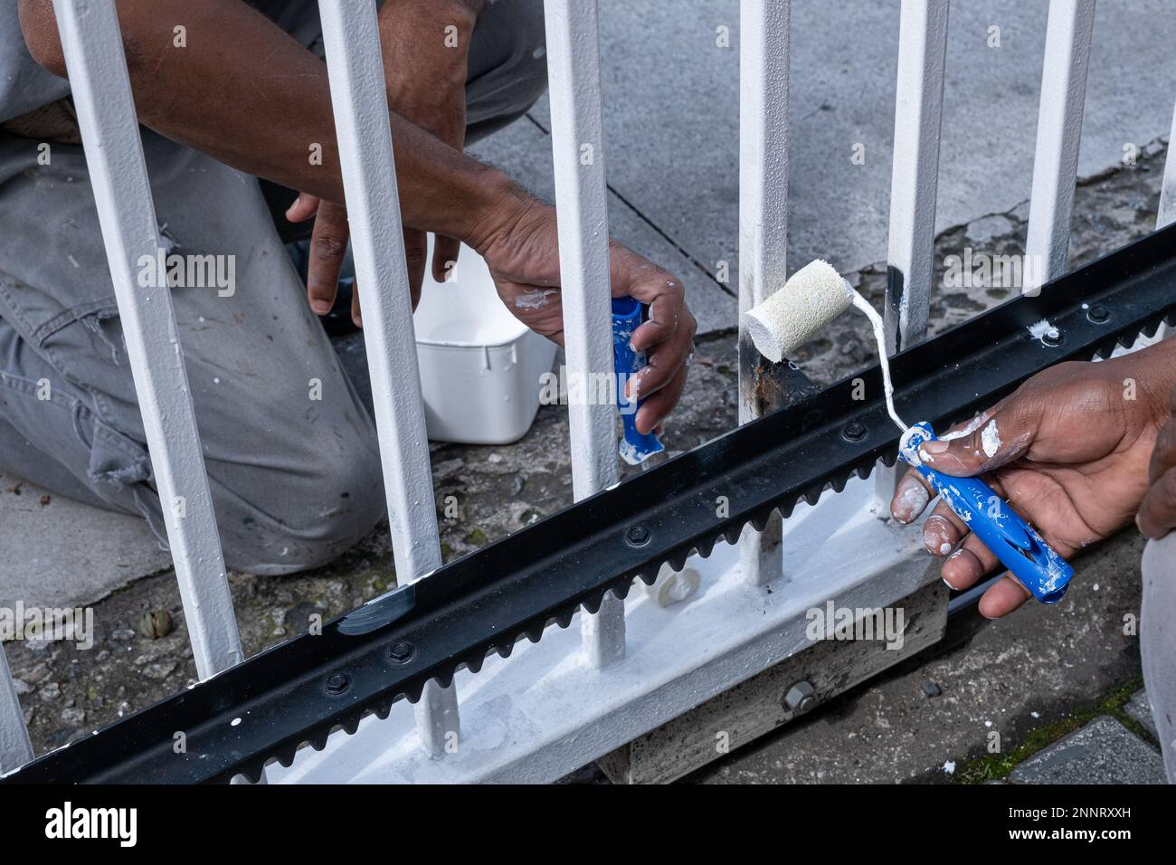 Closeup of hand of painters retouching the electric gate of the condominium garage. Stock Photo