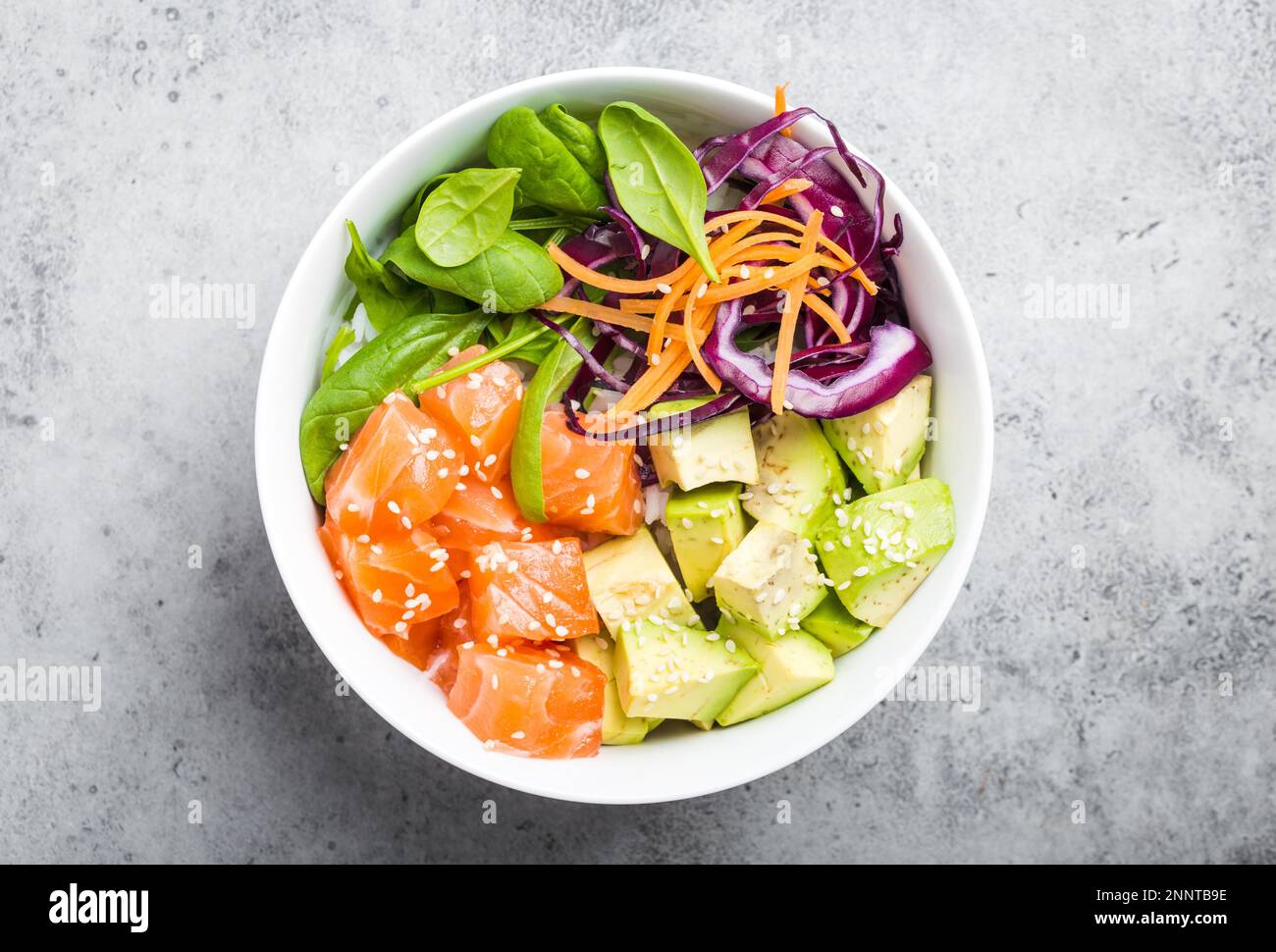 Top view of poke bowl with fresh raw salmon, avocado, rice, spinach ...