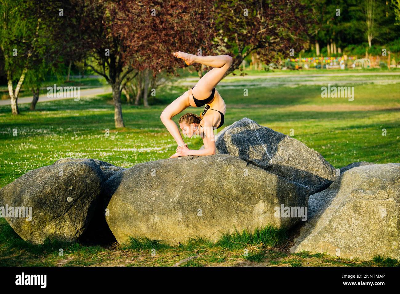 Female contortionist stretching on boulder, Battle Point Park, Bainbridge Island, Washington, USA Stock Photo