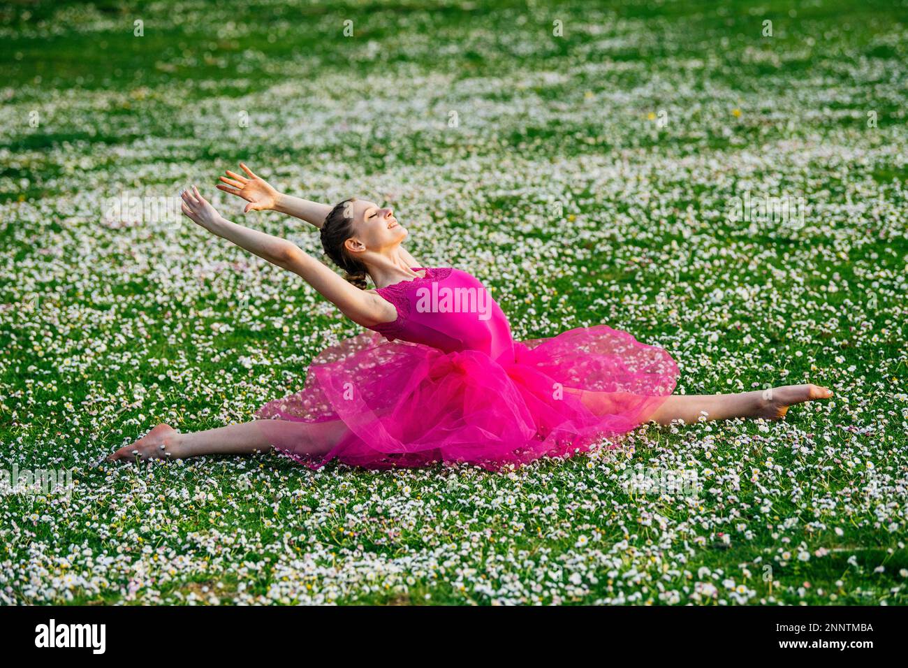 Ballerina doing splits on lawn with flowers, Battle Point Park, Bainbridge Island, Washington, USA Stock Photo